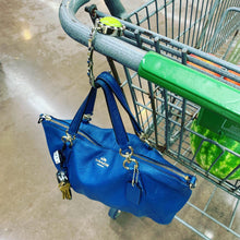 blue purse hanging from a shopping cart with a purse hook