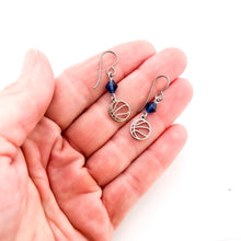 close up of hand holding stainless steel basketball charm earrings with navy blue Swarovski crystal beads and niobium ear wires