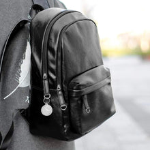 close up of a black backpack with an acrylic photo keychain