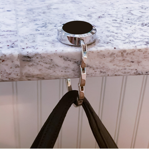 close up of purse hook hanging off a granite countertop