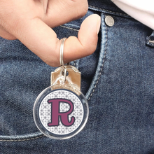 close up of a personalized acrylic photo keychain hanging from a young man's finger