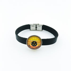 black leather cuff bracelet with stainless steel pickleball slide charm in yellow and orange Rise and shine graphic