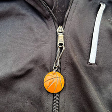 ceramic basketball zipper pull hanging from a black jacket