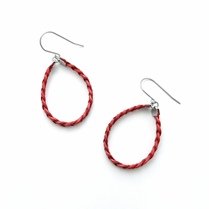 A pair of red braided leather hoop earrings with silver stainless steel accents on a white background.