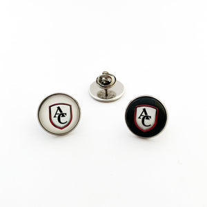 Two stainless steel brooch pins with the Archbishop Curley high school logo, one with white background and one with black background