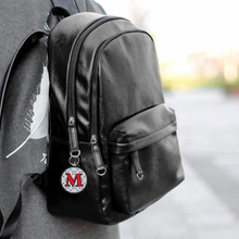 Black backpack with a custom personalized acrylic photo keychain with red capital letter M and black pattern background