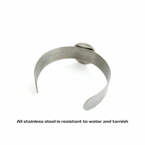 Stainless steel cabochon cuff bracelet on a white background with text about resistance to water and tarnish.