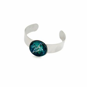 stainless steel cuff bracelet with a leo constellation graphic cabochon in blue and green