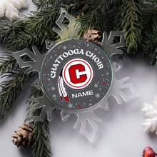 acrylic snowflake shaped Christmas ornament with the 'Chattooga Choir' logo and personalized name, surrounded by greenery and pine cones.