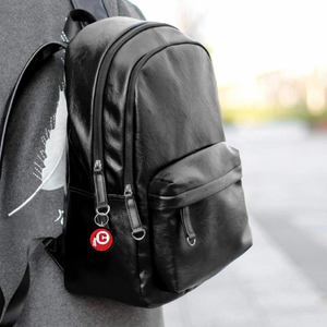 acrylic round keychain with the Chattooga Indian logo hanging from a black leather backpack