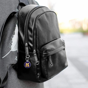 black leather backpack with a personalized acrylic photo keychain hanging from its zipper