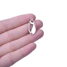 close up of someone holding a stainless steel football pendant charm in their hand