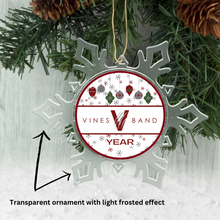 acrylic snowflake shaped ornament with a holiday themed vines high school band graphic in the center hanging from a pine tree