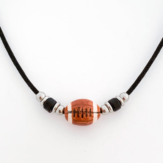 ceramic football bead necklace with black tube bead and stainless steel spacer beads accents strung on a black cotton cord