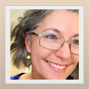 female wearing glasses and tennis bead earrings with silver heart charm