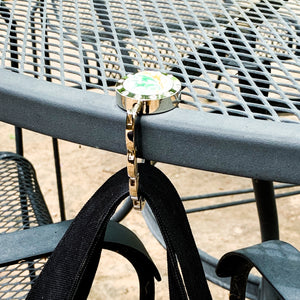 silver purse hook hanging from outdoor patio table