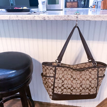 brown Coach purse hanging from purse hook at a kitchen bar
